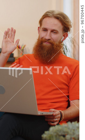 Man sitting on home couch, looking at camera, making video conference call with friends or family Man sitting on home couch, looking at camera, making video conference call with friends or family 96700445