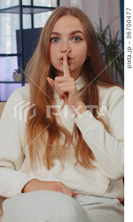 Young woman presses finger to lips makes silence hush sign do not tells gossip secret, quiet at home 96700477