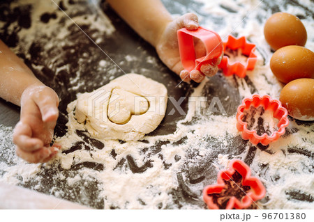 Kids hands cutting out shapes and making cookies. Making biscuits for christmas decorations. Kids hands cutting out shapes and making cookies. Making biscuits for christmas decorations. 96701380