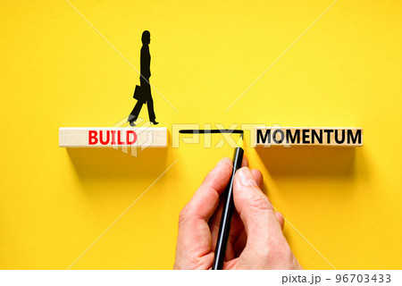 Build momentum symbol. Concept words Build momentum on wooden blocks. Beautiful yellow table yellow background. Businessman hand. Business and build momentum concept. Copy space. 96703433