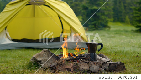Tent and bonfire on the forest lawn in the mountains 96703591