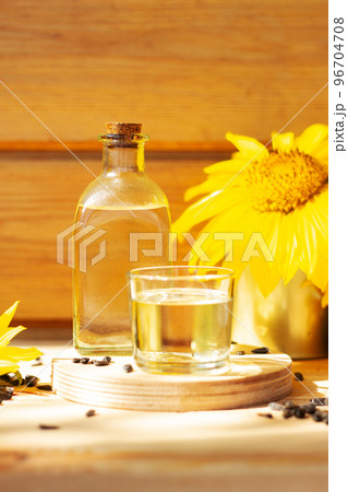 Close-up of sunflower oil in a bottle glass with seeds and sunflower on wooden background 96704708