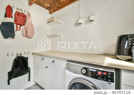 Interior of light kitchen with modern cupboards and appliances located near dining room in modern flat at daytime Interior of light kitchen with modern cupboards and appliances located near dining room in modern flat at daytime 96705116