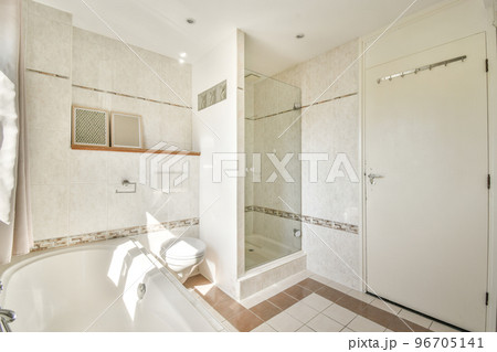 Contemporary bathroom with bathtub and glass shower cabin with light beige tile and white ceiling 96705141