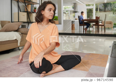 Young woman doing twist yoga pose when exercising at home Young woman doing twist yoga pose when exercising at home 96714590
