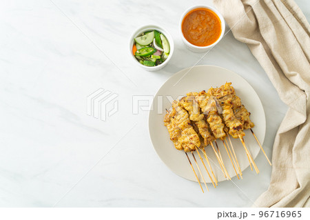 Pork satay with peanut sauce pickles which are cucumber slices and onions in vinegar 96716965