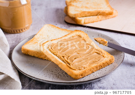 Peanut butter sandwich on toasted bread on a plate and jar of butter on the table Peanut butter sandwich on toasted bread on a plate and jar of butter on the table 96717705