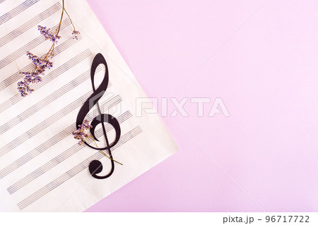 Paper musical clef on a sheet of music and dried flowers. Top view. 96717722