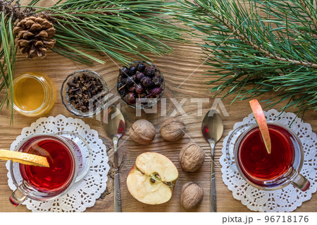 Two glass of mulled wine with cinnamon sticks, slice of oranges and apple, star anise on a wooden table 96718176