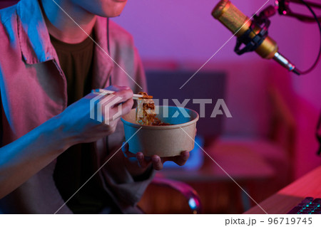Cropped image of videogamer eating noodles when filming video for his blog 96719745