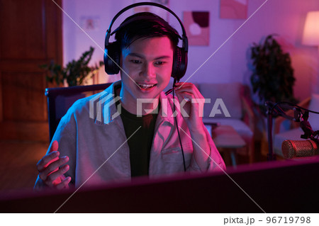 Excited teenage boy speaking in microphone when playing videogame with friend Excited teenage boy speaking in microphone when playing videogame with friend 96719798