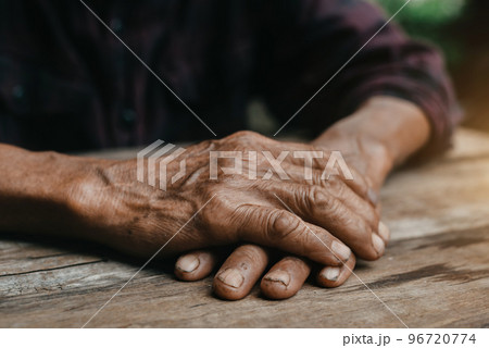 Close-up of old man's hands resting on wood. Close-up of old man's hands resting on wood. 96720774