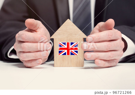 Businessman hand holding wooden home model with English flag. insurance and property concepts 96721266