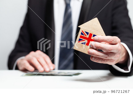 Businessman hand holding wooden home model with English flag. insurance and property concepts 96721267