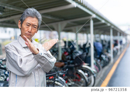 駐輪場でバツ印を見せる管理者のシニア男性 96721358