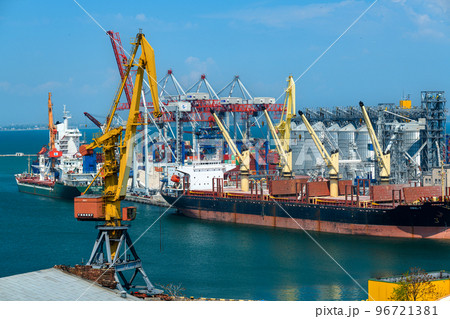 Odessa, Ukraine, May 4, 2019 - industrial seaport infrastructure, sea, cranes and dry cargo ship, grain silo, bulk carrier vessel and grain storage elevators, concept of maritime cargo transportation 96721381