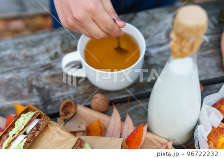picnic in the autumn season, food on a wooden table, hot tea, pastries and sandwiches 96722232