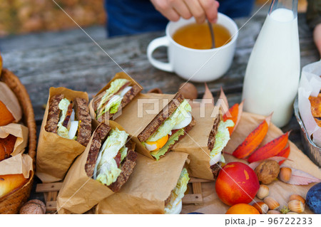 picnic in the autumn season, food on a wooden table, hot tea, pastries and sandwiches 96722233
