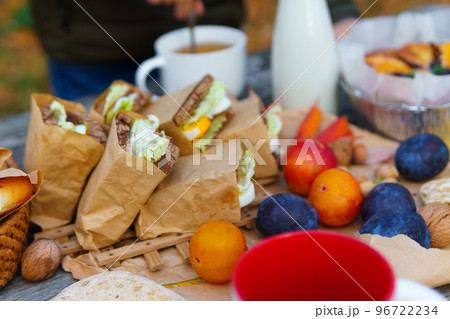 picnic in the autumn season, food on a wooden table, hot tea, pastries and sandwiches 96722234