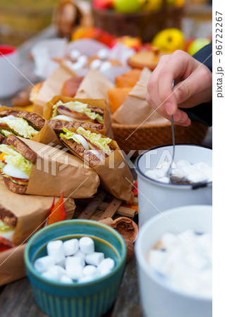 picnic in the autumn season, food on a wooden table, hot tea, pastries and sandwiches 96722267