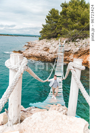 man walking by suspension bridge 96723424