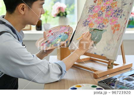 Image of pleased man artist painting picture with watercolor on canvas in art workshop. Art, creative hobby and leisure activity concept 96723920