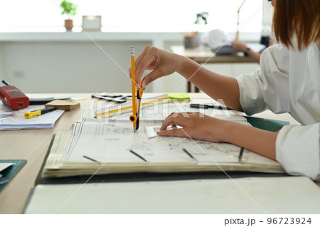 Cropped shot of architect woman using laptop and working on blueprint at her workstation 96723924