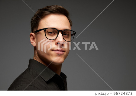 Closeup. Young businessman in black business classic style shirt looks at camera with confident look isolated over grey background. Fashion look of businessman. 96724873