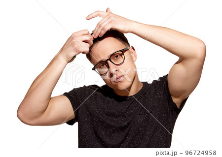 Young handsome man in casual T-shirt combs his hair with hands. Well-being. Concept of men's health, body and hair care Young handsome man in casual T-shirt combs his hair with hands. Well-being. Concept of men's health, body and hair care 96724958