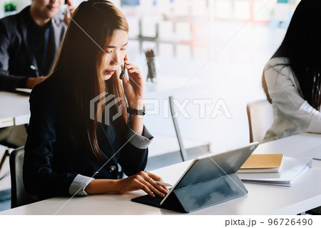 Young asian woman working in call centre, surrounded by colleagues. Young asian woman working in call centre, surrounded by colleagues. 96726490