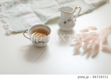 cup with coffee and milk jug on a white wooden background, closeup. Energy breakfast, morning routine concept 96728552