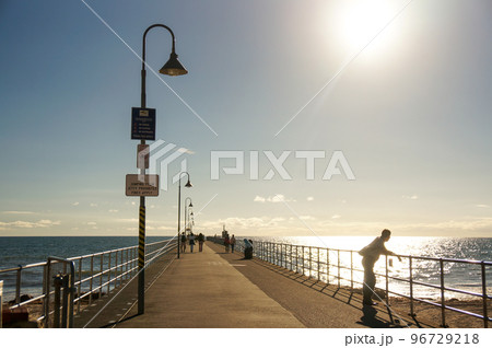 突堤で佇む夕日に照らされた男性 96729218