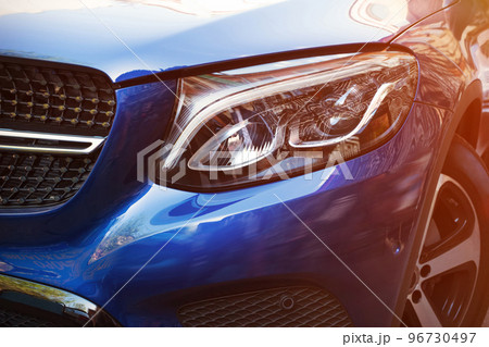 Beautiful headlight of blue car by close-up in a sunny day. Kind with to the side Beautiful headlight of blue car by close-up in a sunny day. Kind with to the side 96730497