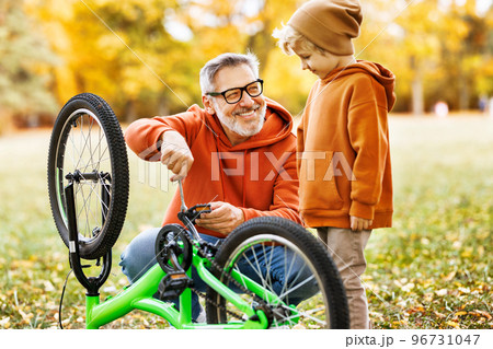 grandfather and grandson repair bicycle outdoors in the autumn park 96731047