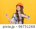 happy teen girl in helmet and checkered shirt pointing finger on copy space, advert 96731268