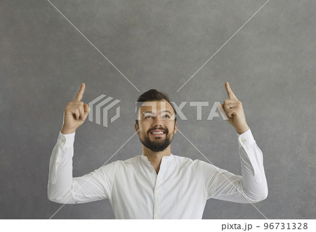 Happy young man smiling and pointing up with both index fingers at copy space above 96731328