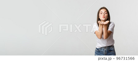 Tender attractive young woman blowing air kiss at camera flirty 96731566