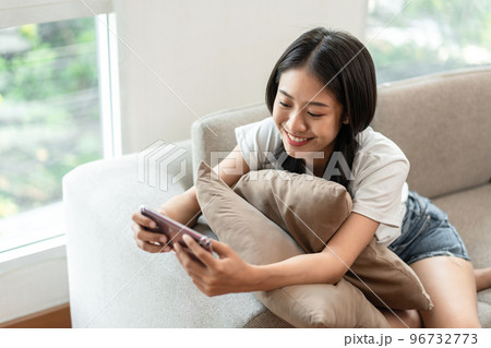 Half-Japanese woman sitting on the sofa using mobile while on vacation, Rest at home, Living room, Relax time, Touch screen tablet, Go on internet, Favorite corner, Personal space Half-Japanese woman sitting on the sofa using mobile while on vacation, Rest at home, Living room, Relax time, Touch screen tablet, Go on internet, Favorite corner, Personal space 96732773