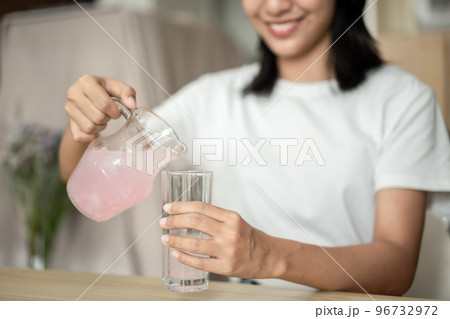 Half Asian woman drinking juice and eating crackers (Healthy whole grain) for breakfast before going to work, Small room in condominium background, Wake-up activities Half Asian woman drinking juice and eating crackers (Healthy whole grain) for breakfast before going to work, Small room in condominium background, Wake-up activities 96732972