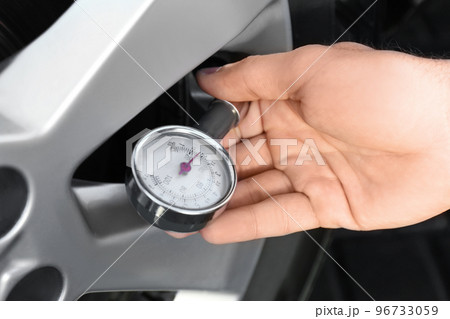 Mechanic checking tire air pressure at car service, closeup 96733059