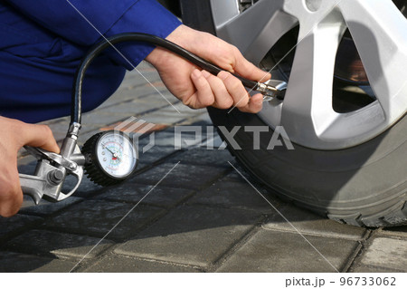 Mechanic checking tire air pressure at car service, closeup 96733062
