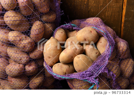 two bags of potatoes on a dark wooden background 96733314