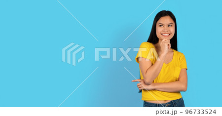 Glad pretty millennial japanese lady student in yellow t-shirt looks at empty space and thinks about new order 96733524