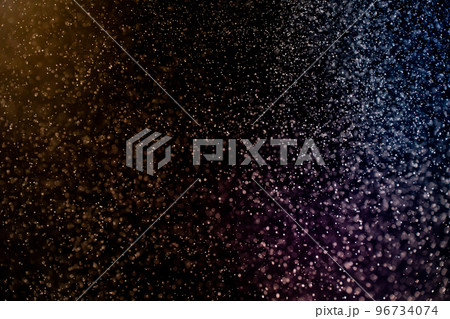 Dust particles floating on a colorful rainbow light on black background. Glittering sparkling flickering overlay. 96734074