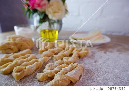 Making homemade cakes. Raw dough, butter, sugar, roses for making brushwood on a wooden tabletop. Concept on a white brick wall background. Homemade food during quarantine and lockdown. 96734352