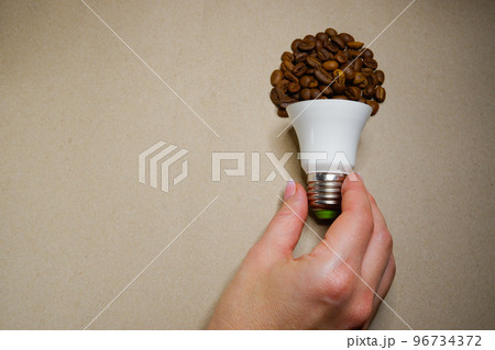 Female hand takes a light bulb from coffee beans on craft paper 96734372