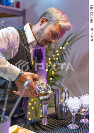 Barman making cocktail Mojito in night club adding ingredients and creating expert drinks on bar counter. 96735695