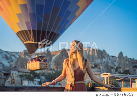 Tourist woman looking at hot air balloons in Cappadocia, Turkey. Happy Travel in Turkey concept. Woman on a mountain top enjoying wonderful view 96736015