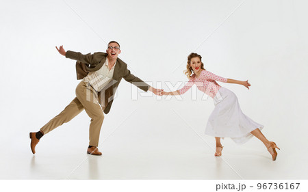 Two emotional dancers in vintage style clothes dancing swing dance, rock-and-roll or lindy hop isolated on white background. 1960s american fashion style and art. Two emotional dancers in vintage style clothes dancing swing dance, rock-and-roll or lindy hop isolated on white background. 1960s american fashion style and art. 96736167