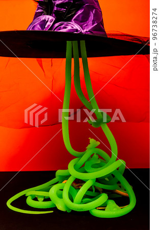Purple witch hat with light green snakes Halloween horrors orange background 96738274